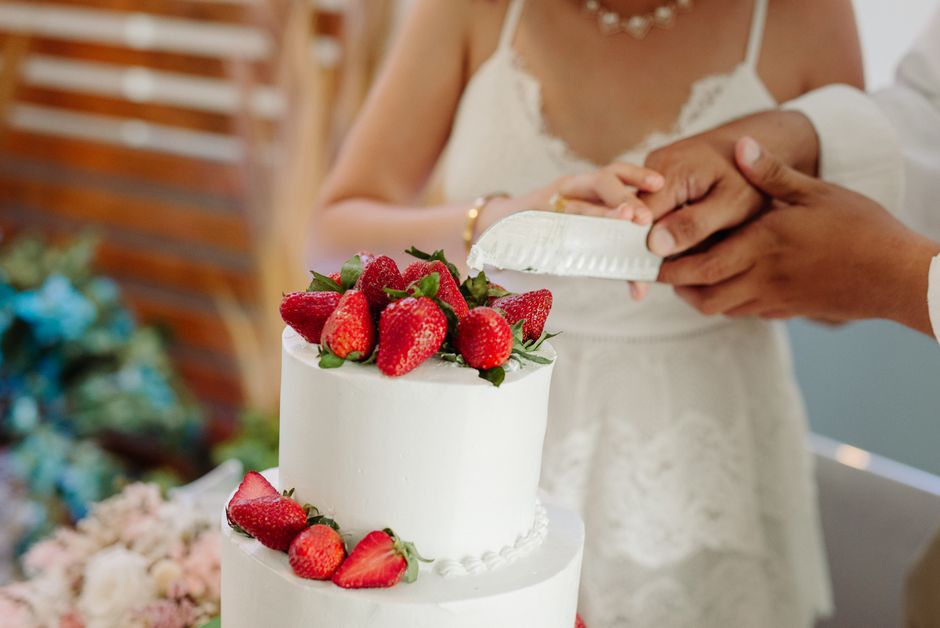 Newlywed couple smiling while cutting their wedding cake